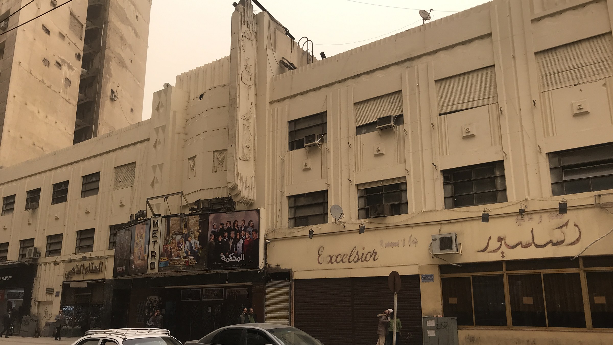 The art deco facade of Cinema Metro in Cairo, with film posters above the entrance and the Excelsior cafe sign next door