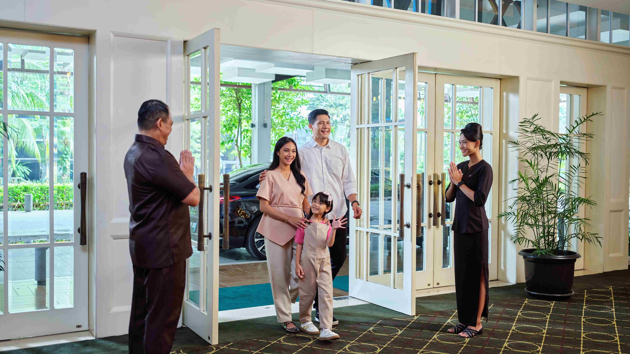 Cinema XXI staff greeting a family in a cinema lobby