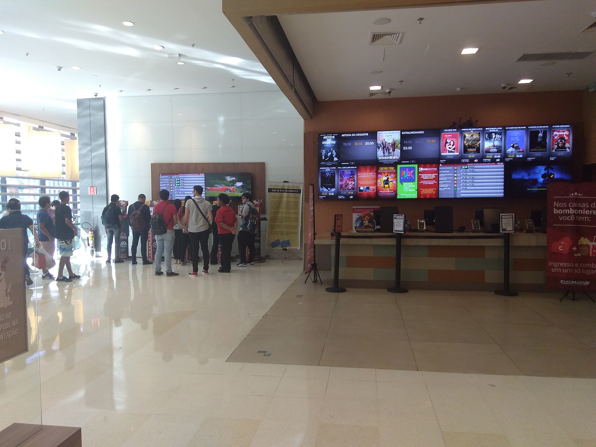 Customers queue at a cinema box office in a São Paulo shopping centre, under screens showing film posters