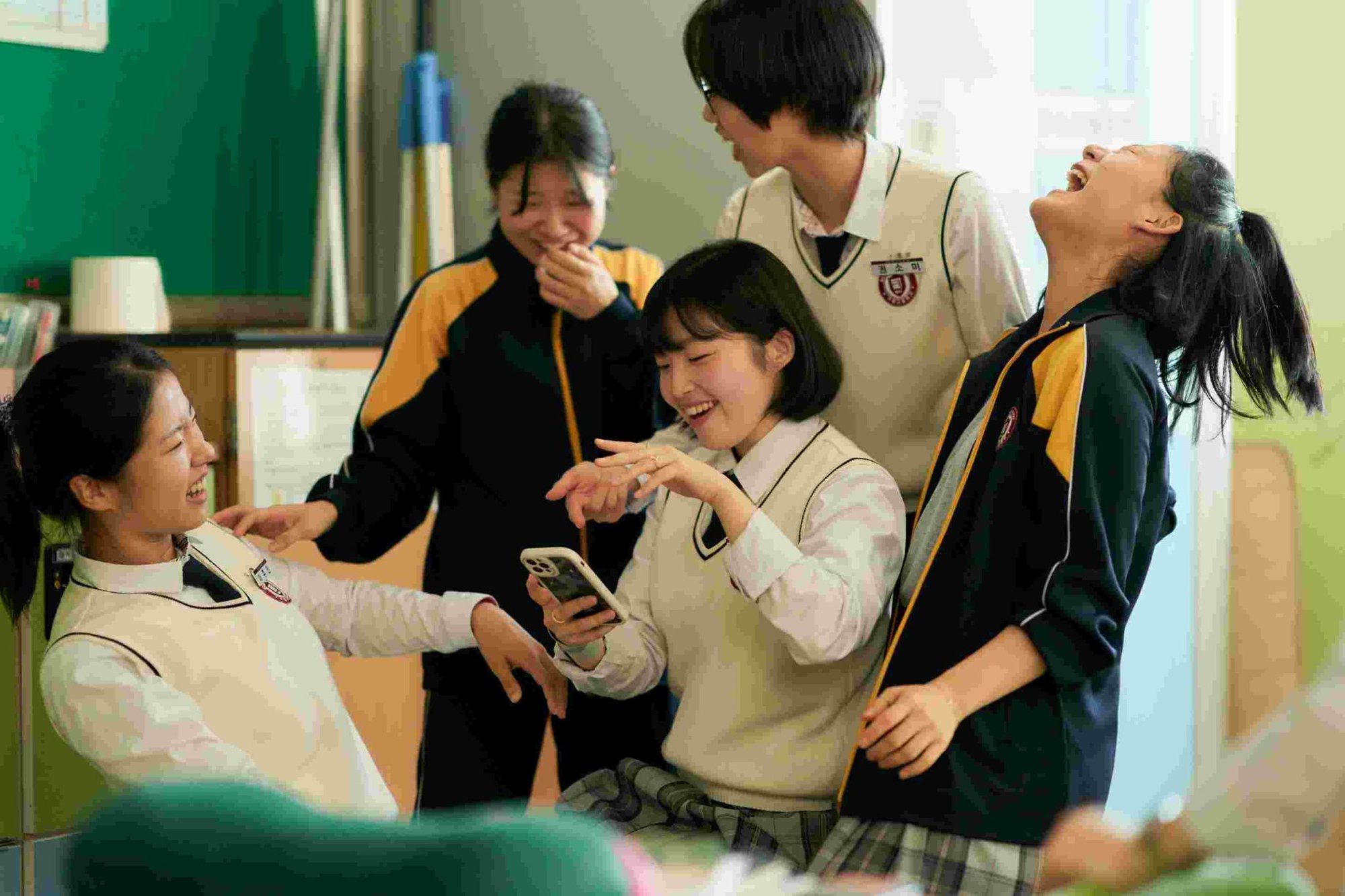 High-school students laughing together in a classroom in The World of Love